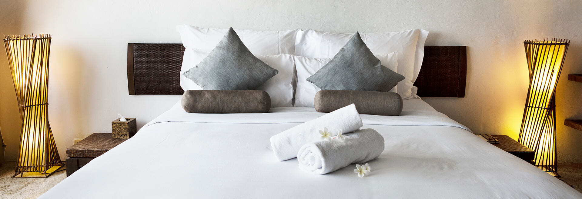 Hotel suite bed with white linens and rolled towels