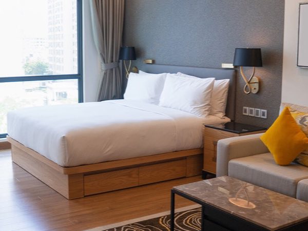 Hotel guest room with a wood bed base, nightstands and a headboard wall