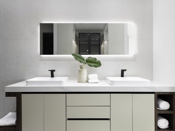 Long cream double vanity with a backlit mirror and open niches